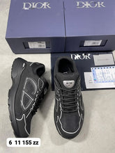 Load image into Gallery viewer, Pair of black Dior trainers with white piping, displayed with original navy box, dust bag, white care pouch, and Dior documentation cards.